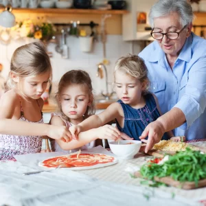 grand-mère et petits enfants qui cuisinent une pizza ferme Sereine